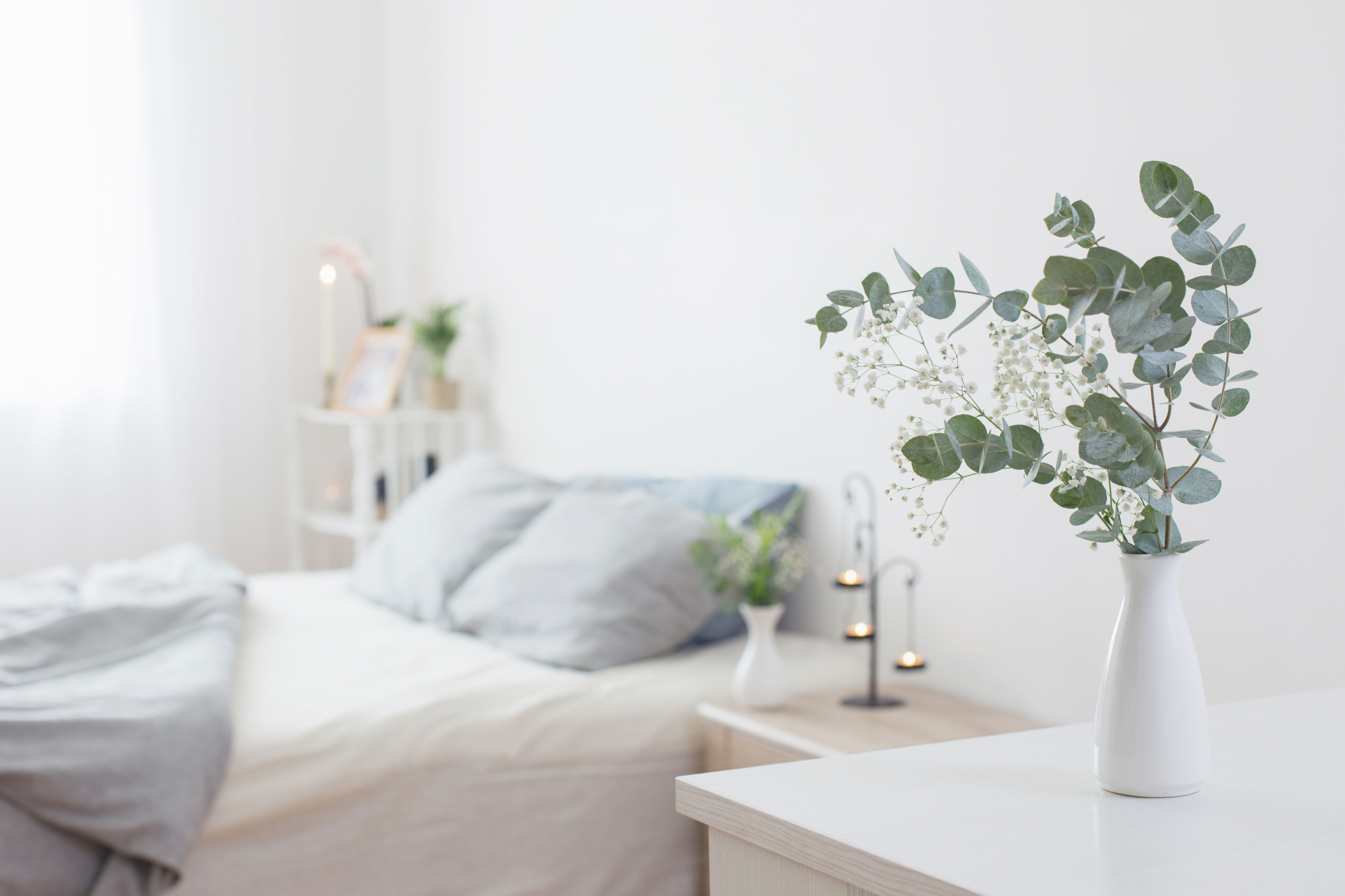 eucalyptus-and-gypsophila-in-vase-in-white-bedroom-with-gold-accents-in-background.